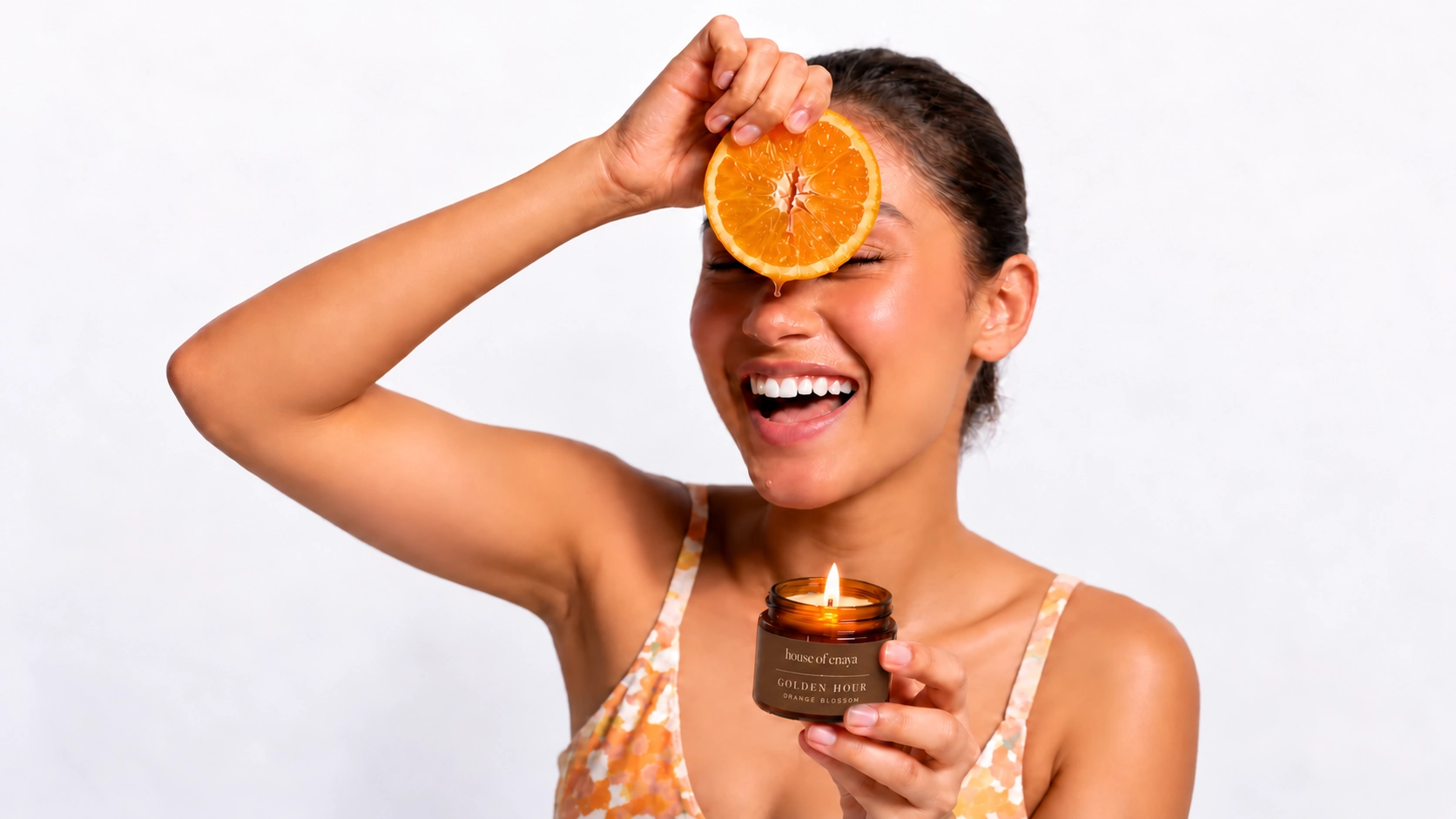 Enaya laughing with an orange slice and the GOLDEN HOUR candle